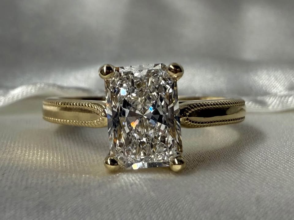 Gold ring with a large diamond on a silver satin background